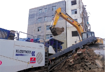挖掘機向可移動式破碎機喂料槽填送大塊建筑垃圾